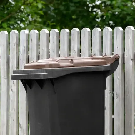 Biotonne vor Gartenzaun 